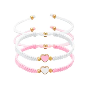 Detail van handgemaakte gevlochten armbanden met hartvormige bedeltjes in roze en wit.