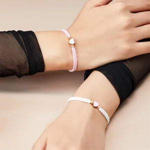 Gedetailleerd zicht op verstelbare roze en witte hartbedelarmbanden om de pols