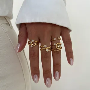 Nahaufnahme eleganter goldener Zirkonringe an der Hand, feine Textur und Design im Detail.