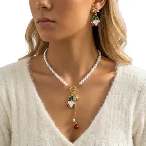 Primo piano del set collana e orecchini di perle natalizie con ciondoli su modella