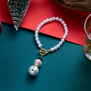 Dettaglio dell'elegante bracciale di perle con pupazzo di neve natalizio e chiusura a T oro.