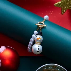 Dettaglio di un ciondolo in perle a forma di pupazzo di neve di Natale con chiusura oro
