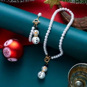 Dettaglio dell'elegante set di gioielli di perle natalizie con ciondoli a forma di pupazzo di neve.