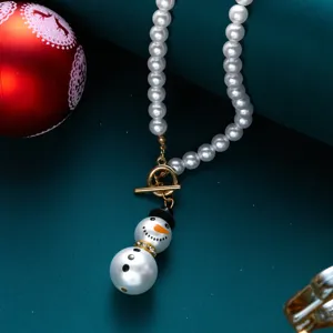 Dettaglio di una collana di perle festiva con un simpatico ciondolo a forma di pupazzo di neve.