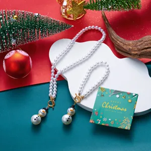 Dettaglio di set collana e bracciale di perle bianche con ciondoli festivi a pupazzo di neve