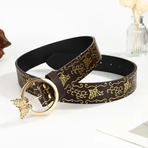 Close-up of vintage brown leather belt with gold butterfly embossing and jeweled buckle