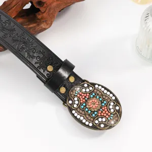 Dettaglio cintura nera intagliata vintage con fibbia in pietra colorata.