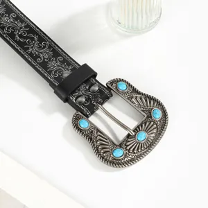 Close-up of Western cowboy belt with embossed floral patterns and turquoise buckle