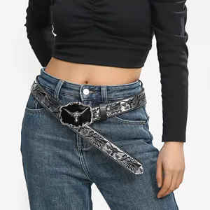 Detailed shot of Western cowboy embossed leather belt with bull head buckle on jeans.