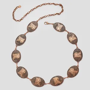 Gros plan d'une chaîne de taille vintage en bronze avec des médaillons gravés R