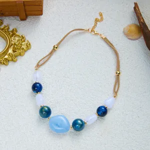 Detailansicht der Boho-Halskette mit blauen und transluzenten Perlen auf beigem Band.