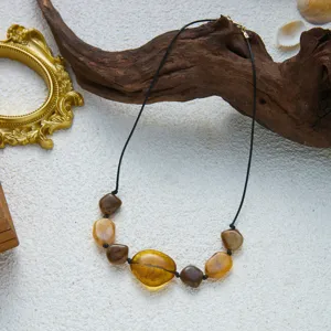 Detaillierte Makroansicht einer Vintage-Böhmen-Kette mit bernsteinfarbenen Acrylperlen.
