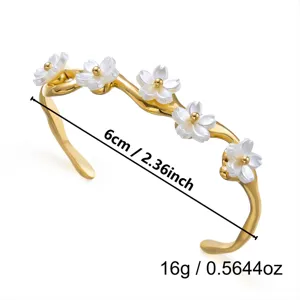 Detailansicht eines goldenen Edelstahlarmbands mit weißen Blumen und 6 cm Durchmesser