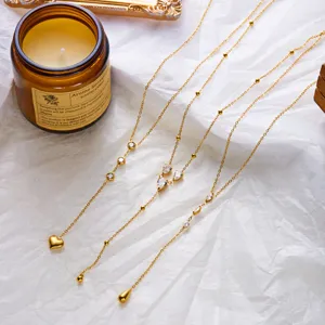 Detail of three gold-plated stainless steel Y-necklaces with heart and teardrop pendants