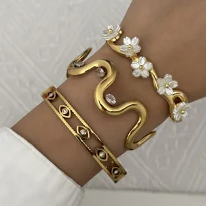Detailaufnahme von drei schicken goldenen Edelstahlarmbändern mit Blumen- und Augenmotiven