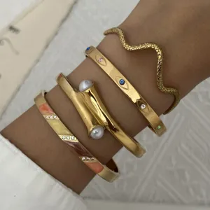 Detail van stapelbare vintage goudkleurige roestvrijstalen armbanden met slang en oog