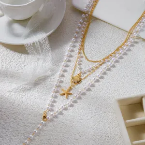 Primo piano di collana a quattro strati con ciondoli a stella marina, conchiglie d'oro e perle
