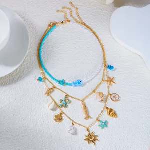 Vista dall'alto di una collana oceanica a strati con catene d'oro e ciondoli a stella.