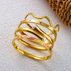 Detailopname van vintage gouden roestvrijstalen armbanden met slangenpatroon en parels