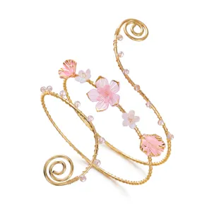 Vista dettagliata di un elegante bracciale da braccio dorato con fiori rosa.