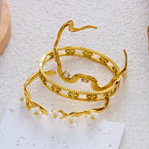 Nahaufnahme von goldenen Edelstahlarmbändern mit Blumen- und geometrischen Mustern