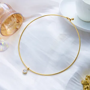 Gros plan d'un collier choker minimaliste en acier inoxydable doré avec pendentif zircon.