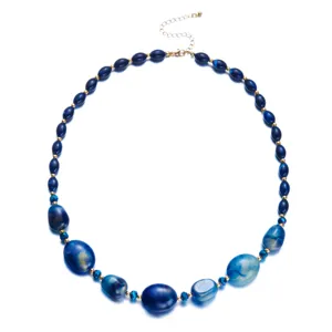 Dettaglio di perle in resina marmorizzata blu e distanziatori dorati su una collana girocollo.