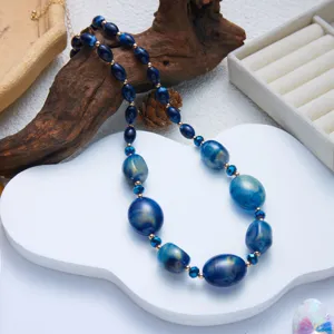 Primo piano di collana di perle in resina blu con venature dorate e design unico
