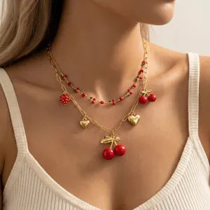 Nahaufnahme einer mehrlagigen Goldkette mit Kirsch-, Erdbeer- und Herzanhängern.