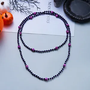 Detailed macro view of Halloween necklace featuring black faceted beads and purple skulls