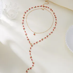 Detailansicht eines modischen goldfarbenen Schmucksets mit roten Kirschperlen für Damen