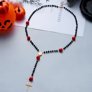 Detail of Halloween rosary necklace with red skulls and crucifix amidst festive props