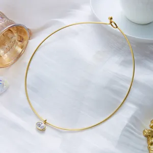 Gros plan d'un collier ras de cou doré en acier inoxydable avec pendentif zircon.
