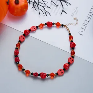 Detailed macro view of a Halloween skull necklace with red beads and orange accents