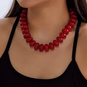 Detailed close-up of a bohemian red resin beaded necklace worn by a female model