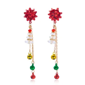 Dettaglio di orecchini natalizi a pendente con campanelli colorati e fiocchi rossi