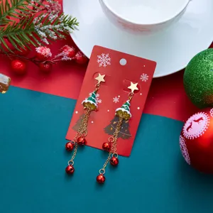 Dettaglio orecchini albero di Natale con nappine a campanella rossa su carta rossa