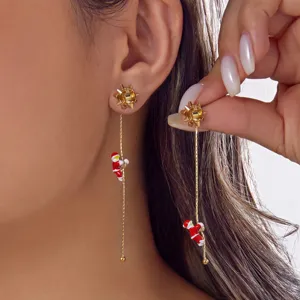 Nahaufnahme von asymmetrischen Goldketten-Ohrringen mit einem Weihnachtsmann-Anhänger