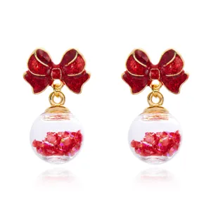 Detailed view of festive red bow earrings with sparkling crystal ball pendants