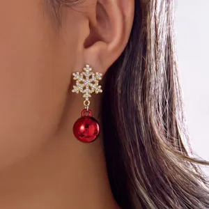 Close-up of a snowflake stud earring with a dangling red festive ball on a person's ear