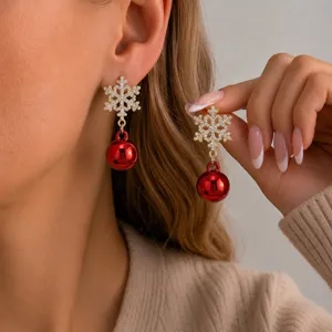 Close-up of elegant Christmas snowflake earrings with festive red ball drop on model