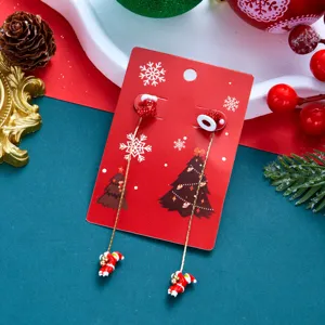Detailaufnahme asymmetrischer Weihnachtsmann-Ohrringe auf einer roten Weihnachtskarte.