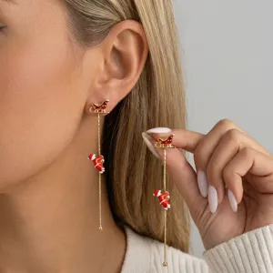 Detailansicht festlicher Weihnachtsmann-Ohrringe mit goldenem Schlitten am Modell