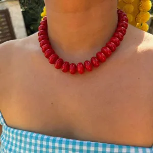Detailed close-up showing a vibrant red resin beaded necklace worn as a stylish choker
