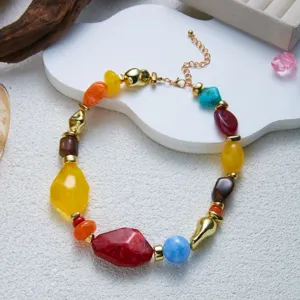 Close-up of colorful irregular resin beads and gold metal spacers on a clavicle chain