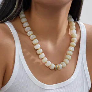 Détail d'un collier en acrylique fait main avec des perles effet marbre crème et touches dorées.