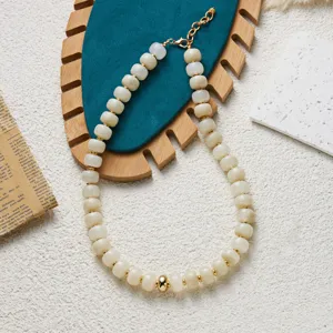 Gros plan de perles en acrylique blanc cassé avec texture jade et entretoises dorées