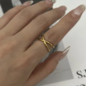 Close-up of a gold stainless steel crisscross X-ring on a female finger for detail view