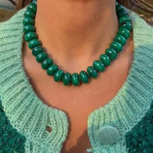 Close-up of green beaded bohemian necklace styled with a textured green sweater