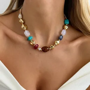 Close-up of a colorful irregular resin bead necklace with gold metallic spheres on a model
